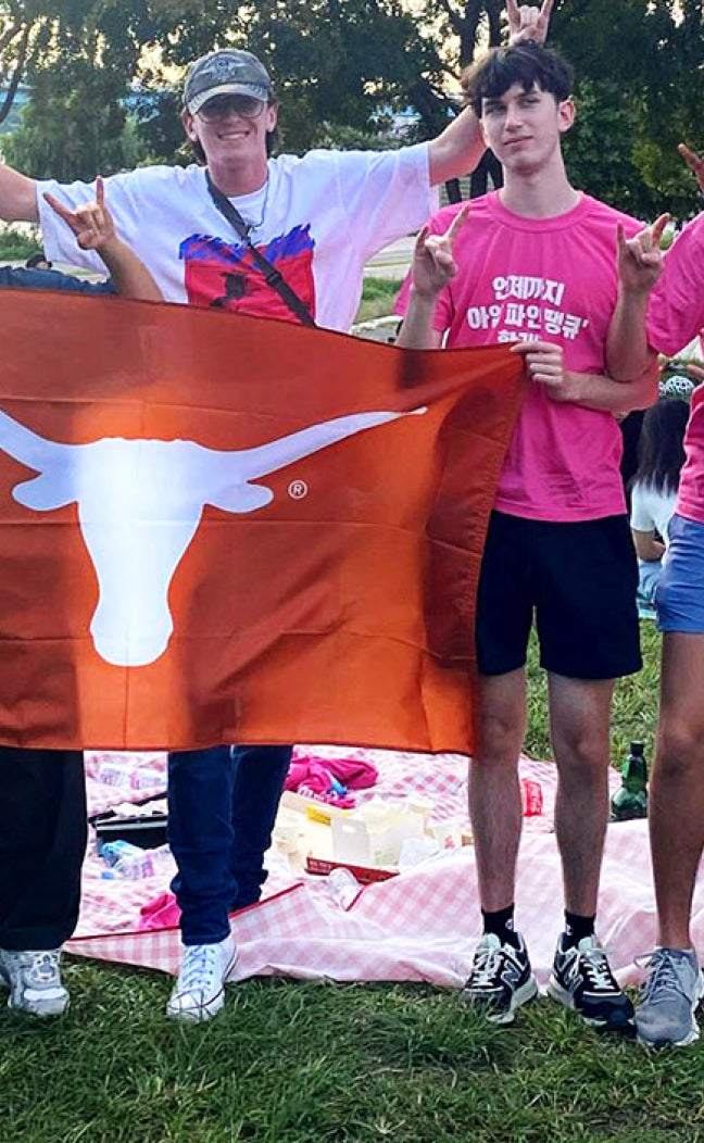 Students with Take the World by the Horns unfurl a Longhorn flag in Seoul