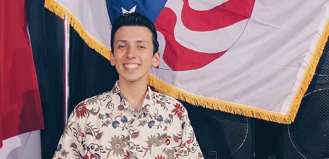 Miguel Robles in front of the Peace Corps flag