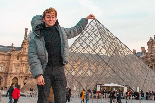 David Zulli poses in front of a monument in Paris, giving the impression he's holding the top of the monument.