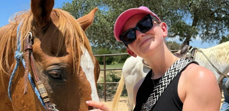 Sarina smiling as she pets a horse, a Bundeswehr participant