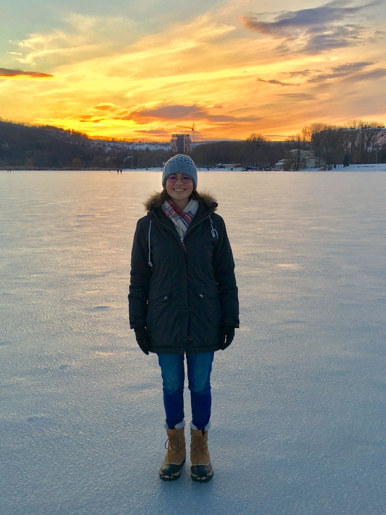 molly stands in front of a snowy town at sunset