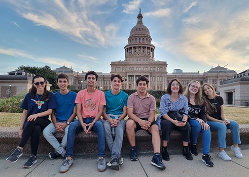 Students sit on bench with Capitol in the background