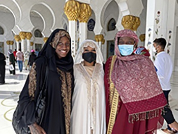Three girl stand together wearing Emirati abayas