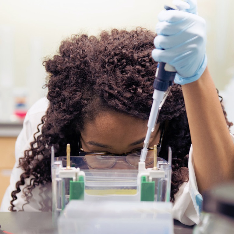 A science major dispenses liquid into vials in a lab