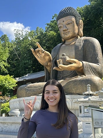 Noemy Lopez-Martinez signs hook 'em with a Buddha statue