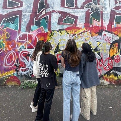 Four students regard a graffiti-laden "peace wall" in Northern Ireland