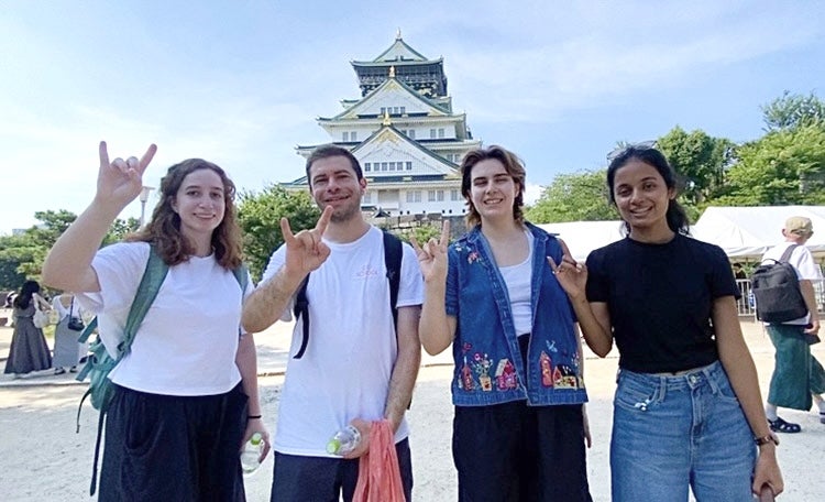 Students pose for a group picture and put up "hook em" hand signs. 