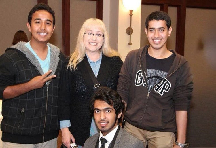 ELC instructor Tracy Frank smiles with three students 