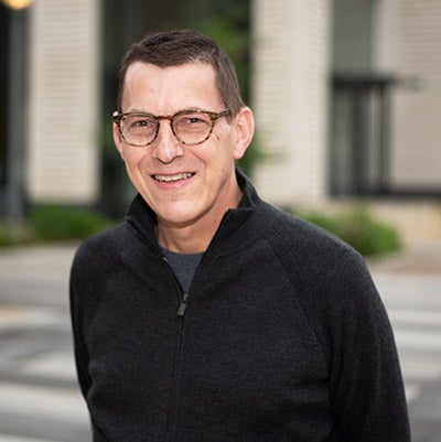Dell Medical School Director Paul Rathouz smiles w/glasses and dark shirt