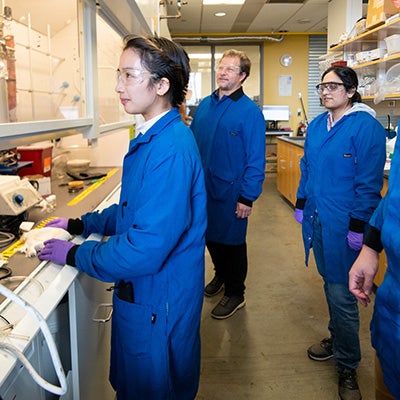 UT Professor Brian Korgel looks on as a researcher works in the lab