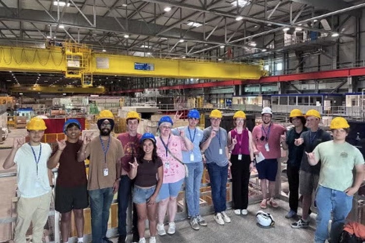 Students hold up "Hook 'Em" hand signs at CERN.