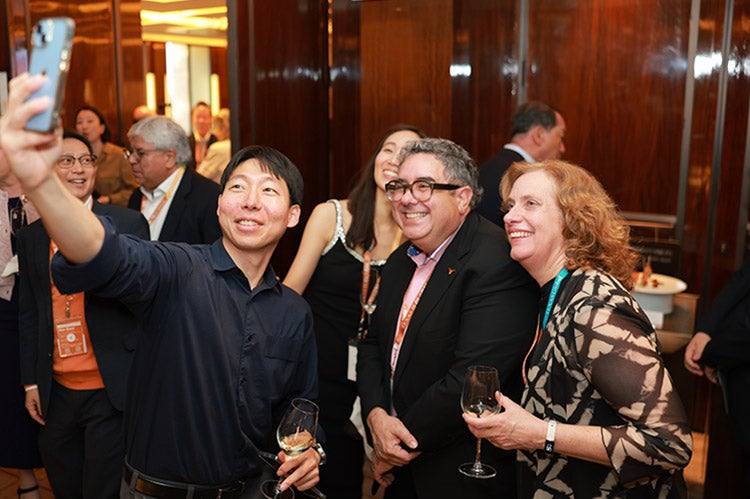 A UT alum, dean and professor take a selfie at the 2026Texas Global Alumni Summit