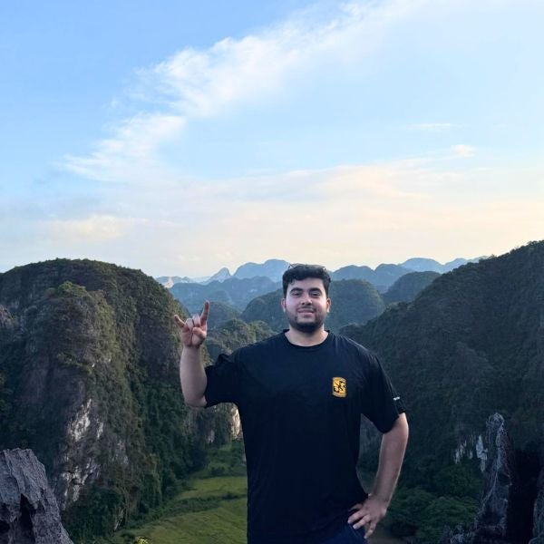 Man in black t-shirt posing on a mountain overlook during clear day.