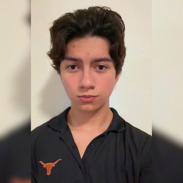 Young man with dark hair wearing a black polo shirt with an orange longhorn logo on a plain white background.